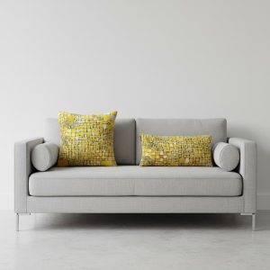 coussin jaune à motif sur canapé gris.